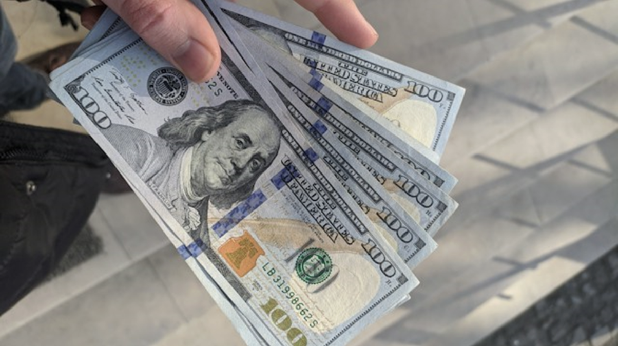 An investor holding hundred-dollar bills